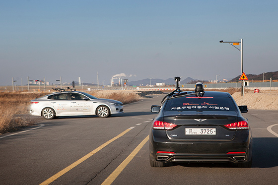 Two self-driving cars at the crossroads are communicating via 5G network to decide which vehicle to first pass through the congested area 