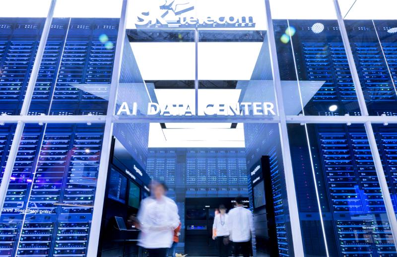 SK텔레콤 AI DATA CENTER 입구. 벽면을 가득 채운 파란 조명의 서버 랙과 내부에서 일하는 직원들이 보인다.