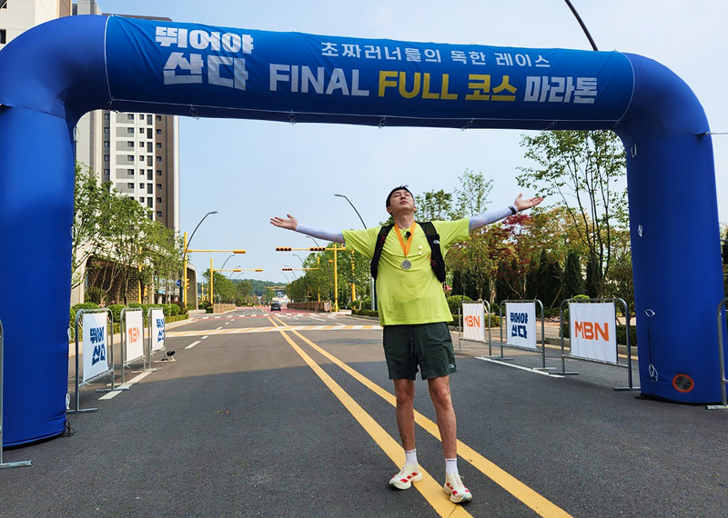 마라톤 결승선에서 두 팔을 벌리고 환호하는 슬리피님의 모습