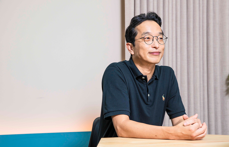 이성호 대표가 테이블에 손을 모은 채 앉아 있으며