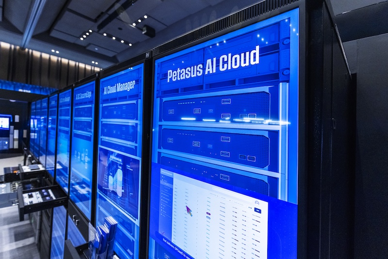 대형 파란 스크린에 ‘AI Cloud Manager’와 ‘Petasus AI Cloud’의 대시보드가 펼쳐져 있다. 클러스터 현황과 리소스 배분을 시각화한 주권형 AI 인프라 관리 화면이다.