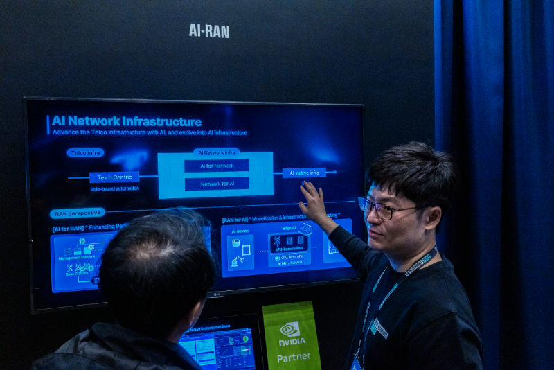 ‘AI Network Infrastructure’ 화면 앞에서 담당자가 ‘AI for Network’와 ‘Network for AI’ 구조를 설명 중이다. 통신 인프라 최적화 개념이 시각화되어 있다.