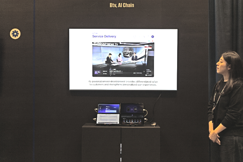 ‘Service Delivery’ 화면에 연합뉴스TV 방송 장면이 보인다. 담당자가 이를 바라보며, 테이블 위 셋톱박스와 장비를 통해 AI 기반 서비스 체인을 시연하고 있다.