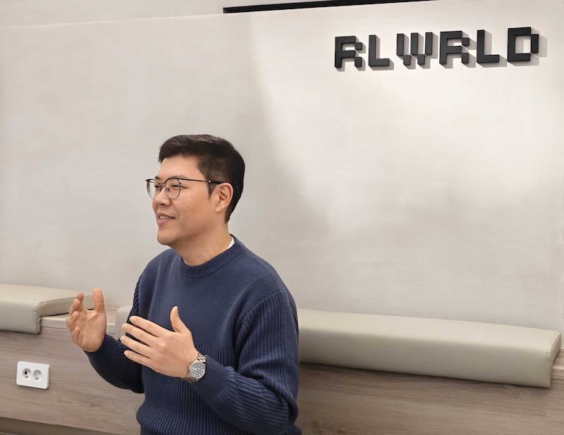 RLWRLD 로고가 걸린 공간에서 류중희 대표가 손짓을 하며 인터뷰를 진행하고 있다.