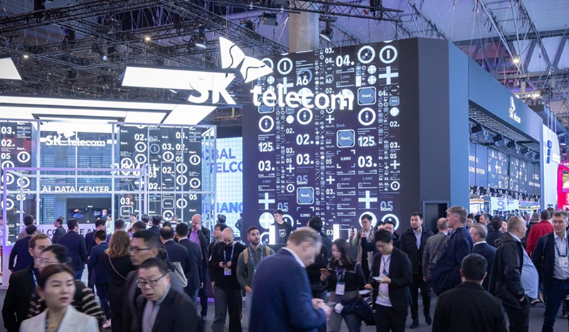MWC25에 참가한 SK텔레콤 부스에 방문객들이 북적이고 있다. 상단에는 SK텔레콤 로고가 표시되어 있다.