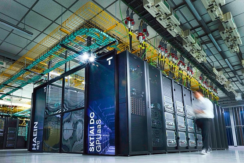 데이터센터 내부에 대형 GPU 서버 랙이 일렬로 배치되어 있으며, 전면 패널에는 'HAEIN 해인', 'SKT AI DC GPUaaS' 문구와 서버 이미지가 인쇄되어 있다.