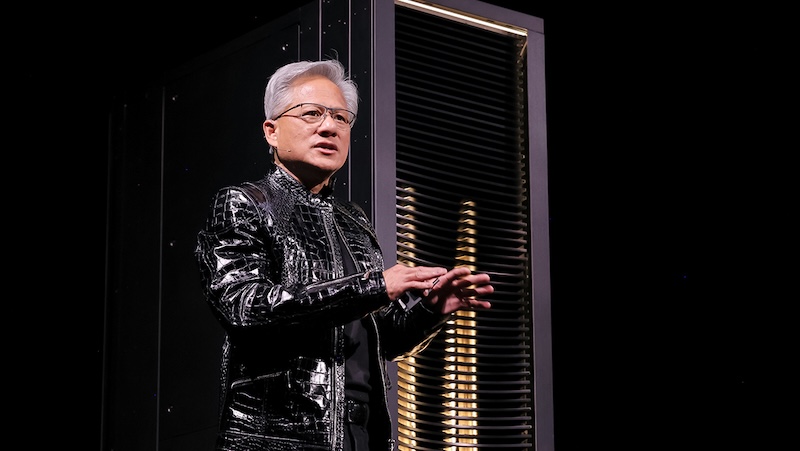 NVIDIA CEO 젠슨 황이 검은 가죽 재킷을 입고 서버 랙을 배경으로 무대에서 발표하고 있는 모습.