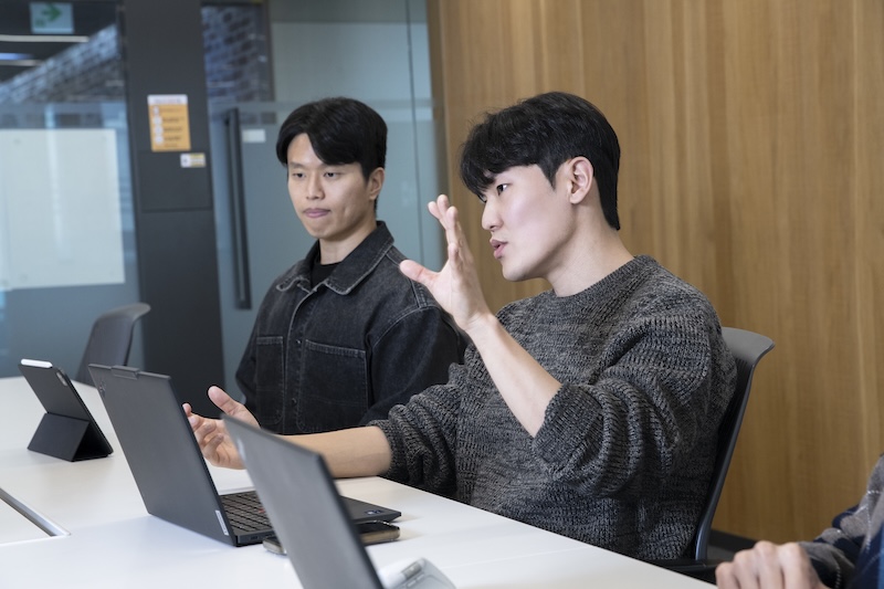회의실 테이블에서 이경필 님이 노트북 앞에서 손짓하며 설명하고, 옆에 오태석 님이 태블릿을 두고 듣는 모습.