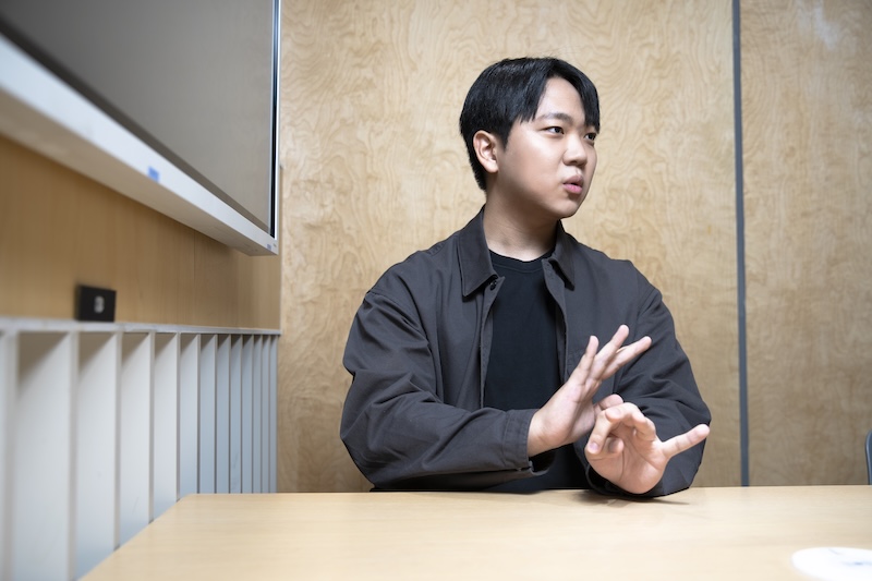 테이블에 앉아 손을 움직이며 설명하는 양현호 님. 검은 셔츠를 입고 진지한 표정으로 대화를 이어가고 있다.