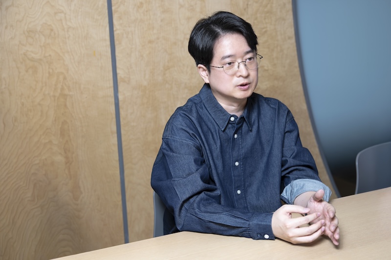 테이블에 앉아 두 손을 모으고 진지한 얼굴로 설명하는 천성준 님.