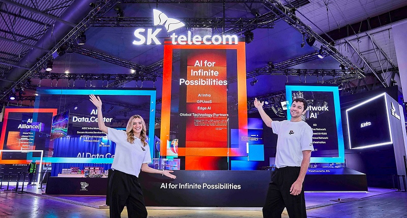 MWC26 SK텔레콤 전시 부스 전경으로 ‘AI for Infinite Possibilities’ 메시지가 표시된 중앙 전시 구조물 앞에서 관계자들이 부스를 소개하는 모습