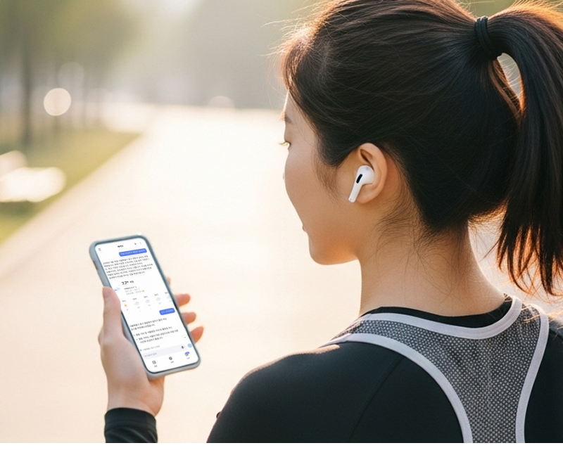 러닝을 시작하기 전 공원 산책로에서 이어폰을 착용한 여성이 스마트폰을 들고 에이닷으로 날씨와 미세먼지 정보를 확인하는 모습